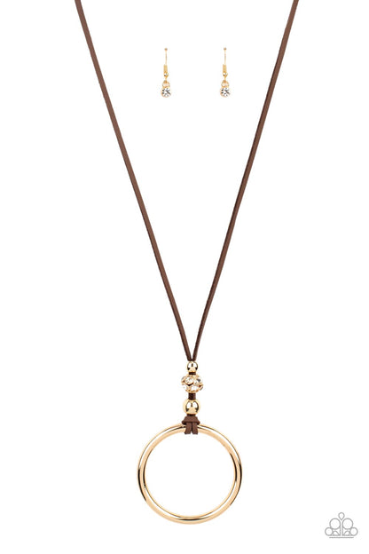BLING Into Focus Brown Necklace - Paparazzi Accessories  Infused with pair of classic gold beads and a white rhinestone encrusted accent, lengthened brown leather cording knots around a bold gold hoop for a knockout look. Features an adjustable clasp closure.  Sold as one individual necklace. Includes one pair of matching earrings.