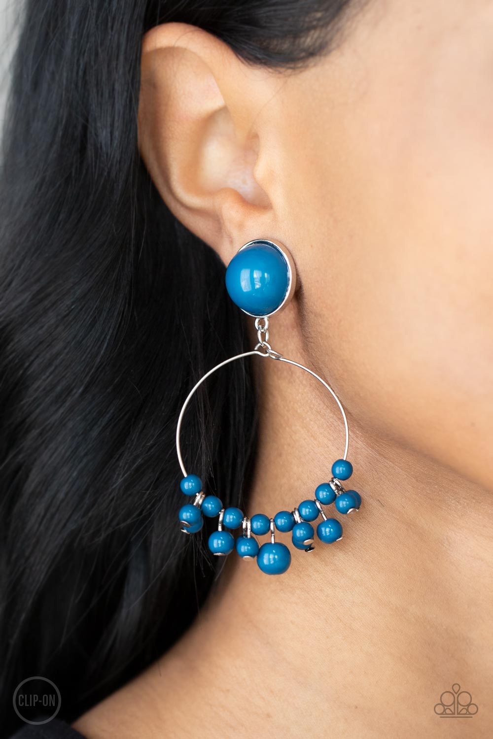 Cabaret Charm Blue Clip-On Earring - Paparazzi Accessories  Shiny blue beads are threaded along a dainty wire hoop that attaches to an oversized blue beaded fitting, creating a bubbly fringe. Earring attaches to a standard clip-on fitting.  Sold as one pair of clip-on earrings.