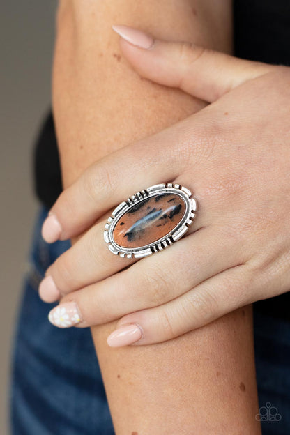 Peacefully Pioneer Brown Ring - Paparazzi Accessories  An earthy brown oval stone is pressed into the center of a textured silver frame, creating an abstract artisanal display atop the finger. Features a stretchy band for a flexible fit.  Sold as one individual ring.