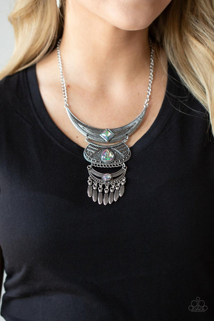Lunar Enchantment Multi Necklace - Paparazzi Accessories  Embossed in studded, geometric, and paisley filigree-like patterns, three mismatched silver half moon plates dramatically link below the collar. Featuring an entrancing green UV shimmer, an oversized collection of square, teardrop, and round rhinestones embellish the decorative silver frames, while a silver beaded fringe swings from the lowermost plate for a noisemaking finish. Includes one pair of matching earrings.