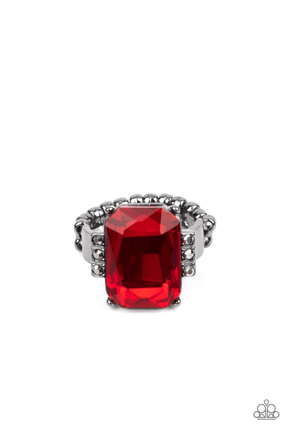 Epic Proportions Red Ring - Paparazzi Accessories  Flanked by stacks of dainty hematite rhinestones, an oversized fiery red emerald cut gem is pressed into the center of a sleek gunmetal frame, resulting in a dramatic centerpiece atop the finger. Features a dainty stretchy band for a flexible fit.  Sold as one individual ring.