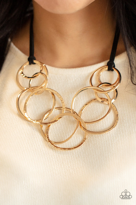 Spiraling Out of COUTURE Gold Necklace - Paparazzi Accessories  Black suede cords knot around a mismatched assortment of hammered gold rings that interlock below the collar, creating two rows of dizzying texture. Features an adjustable clasp closure. Sold as one individual necklace. Includes one pair of matching earrings.  All Paparazzi Accessories are lead free and nickel free!  Sold as one individual necklace. Includes one pair of matching earrings.