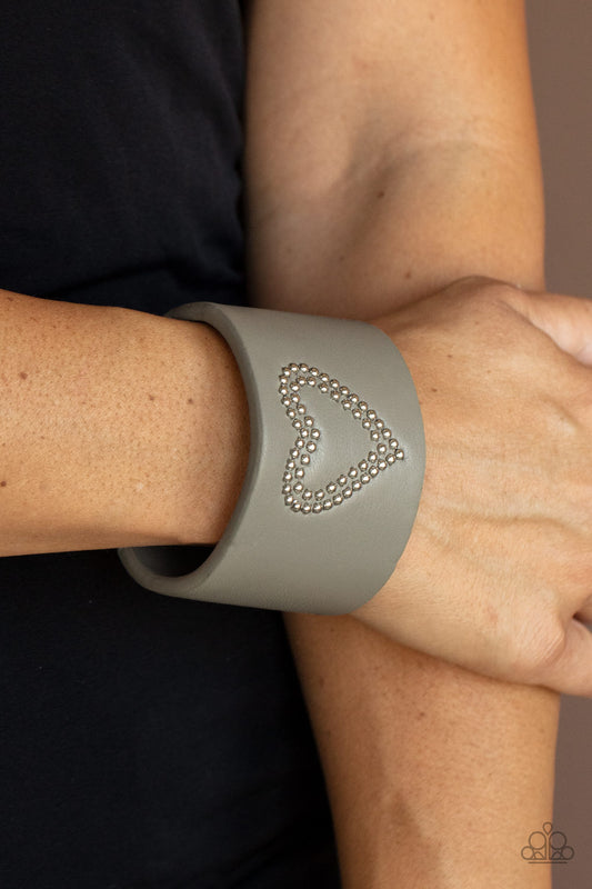 Rodeo Romance Silver Cuff Bracelet - Paparazzi Accessories  The center of an Ultimate Gray leather cuff is studded in a charming heart pattern, creating a rustically romantic look around the wrist.  Sold as one individual bracelet.