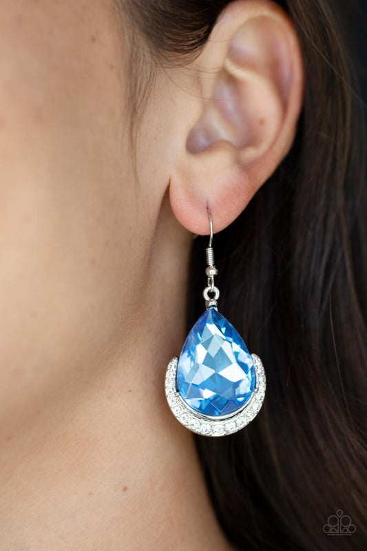 Mega Marvelous Blue Earring - Paparazzi Accessories  Dotted in white rhinestones, a dainty silver bar curves around the bottom of a dramatically oversized blue teardrop rhinestone for a glamorous fashion. Earring attaches to a standard fishhook fitting.  Sold as one pair of earrings.