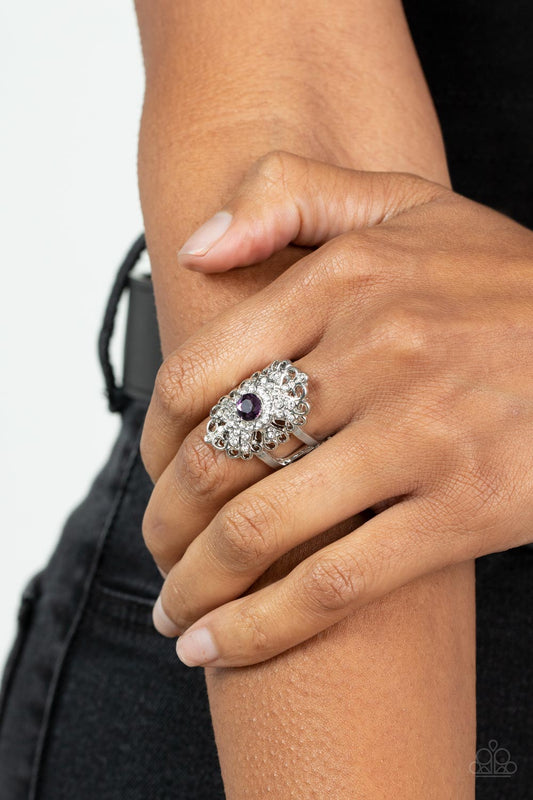 Dining with Royalty Purple Ring - Paparazzi Accessories  A glittery purple rhinestone adorns the center of a frilly silver backdrop adorned in dainty white rhinestones, creating a regal centerpiece atop the finger. Features a stretchy band for a flexible fit.  All Paparazzi Accessories are lead free and nickel free!   Sold as one individual ring.