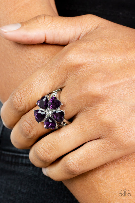 Minnesota Magic Purple Ring - Paparazzi Accessories  Glittery heart-shaped purple rhinestones bloom from a dainty white rhinestone center, creating a sparkly floral centerpiece atop layered silver bands. Features a stretchy band for a flexible fit.  Sold as one individual ring.