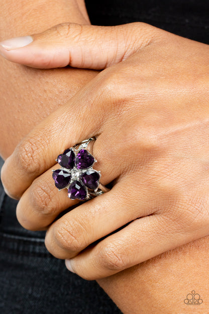Minnesota Magic Purple Ring - Paparazzi Accessories  Glittery heart-shaped purple rhinestones bloom from a dainty white rhinestone center, creating a sparkly floral centerpiece atop layered silver bands. Features a stretchy band for a flexible fit.  Sold as one individual ring.