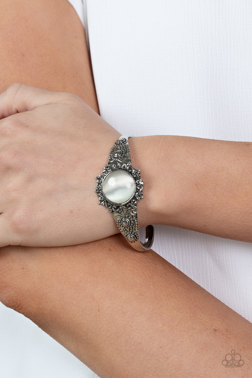 Extravagantly Enchanting - White Item #P9RE-WTXX-169XX A mystical white cat's eye stone is pressed into the floral center of a dainty silver cuff that is abloom with flowery details, creating an enchanting pop of color around the wrist.  Sold as one individual bracelet.