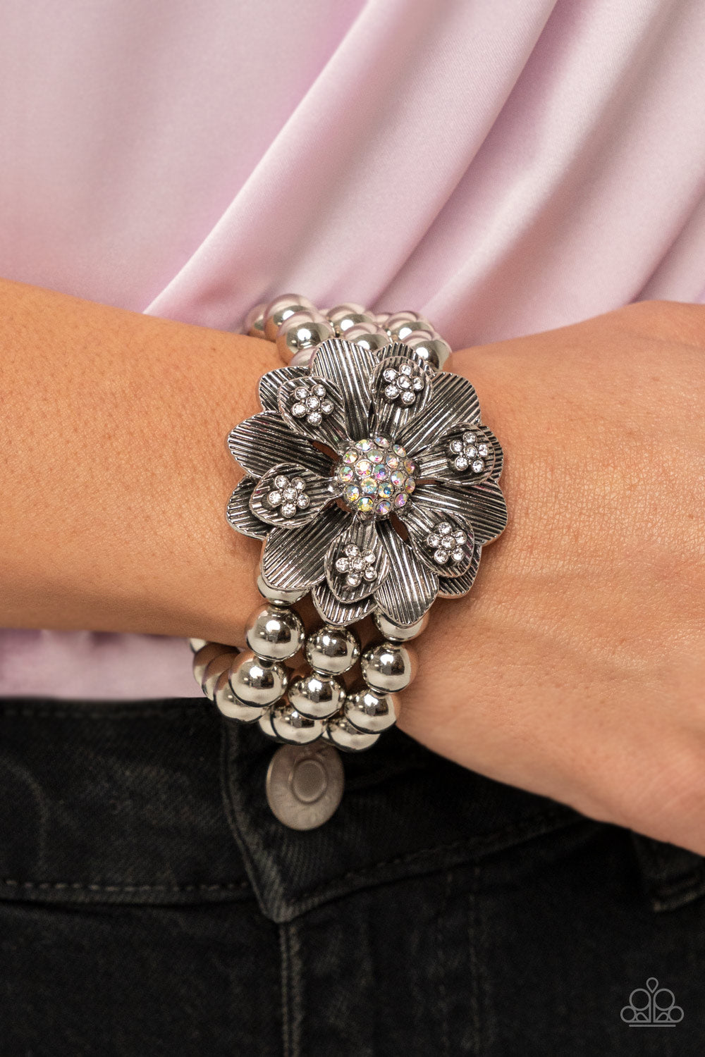 Botanical Bravado Multi Bracelet - Paparazzi Accessories  A daring oversized silver flower is composed of petals lined in antiqued silver and dotted with glistening dainty white rhinestones. A sphere of dainty iridescent rhinestones creates the center of the flower as it sits atop a trio of shiny silver beaded stretchy bands around the wrist for a dramatically whimsical look.  Sold as one individual bracelet.
