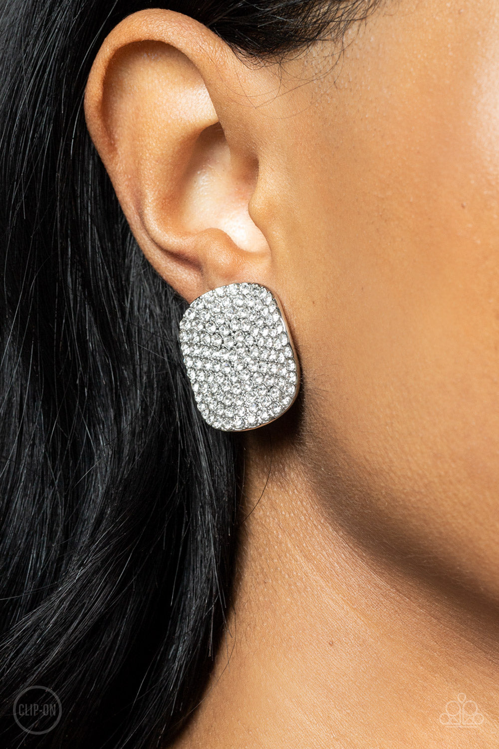 Lunch at the Louvre White Clip-On Earring - Paparazzi Accessories  The front of a warped silver disc is encrusted in row after row of blinding white rhinestones, resulting in a refined display. Earring attaches to a standard clip-on fitting.  Sold as one pair of clip-on earrings.
