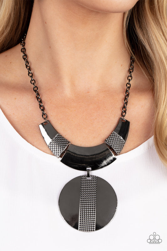 Metallic Enchantress Black Necklace - Paparazzi Accessories  Three curved gunmetal bars, stamped in studded texture accents, connect to a gunmetal chain across the collar. An oversized gunmetal disc, divided down the center with texture, swings from the bottom resulting in an edgy modern finish. Features an adjustable clasp closure.  Sold as one individual necklace. Includes one pair of matching earrings.