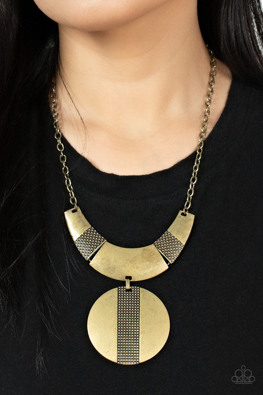 Metallic Enchantress Brass Necklace - Paparazzi Accessories  Three wide, curved brass bars, stamped in studded textured accents, connect to a brass chain across the collar. A substantial brass disc, divided down the center with texture, swings from the bottom resulting in an edgy modern finish. Features an adjustable clasp closure.  Sold as one individual necklace. Includes one pair of matching earrings.