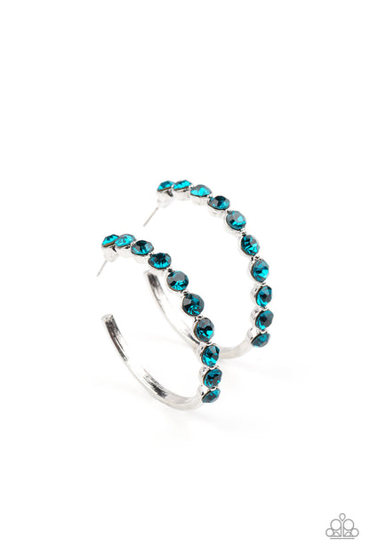 Photo Finish Blue Hoop Earring - Paparazzi Accessories  The front of a bold silver hoop is encrusted in glittery blue rhinestones, creating a glamorous pop of sparkle. Earring attaches to a standard post fitting. Hoop measures approximately 1 3/4" in diameter.  Sold as one pair of hoop earrings.