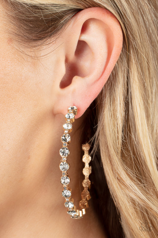 Royal Reveler Gold Earring - Paparazzi Accessories  Encased in sleek gold fittings, a glamorous collection of glittery white rhinestones delicately coalesce into an oversized hoop for a sparkly statement. Earring attaches to a standard post fitting. Hoop measures approximately 2 1/2" in diameter.  Sold as one pair of hoop earrings.