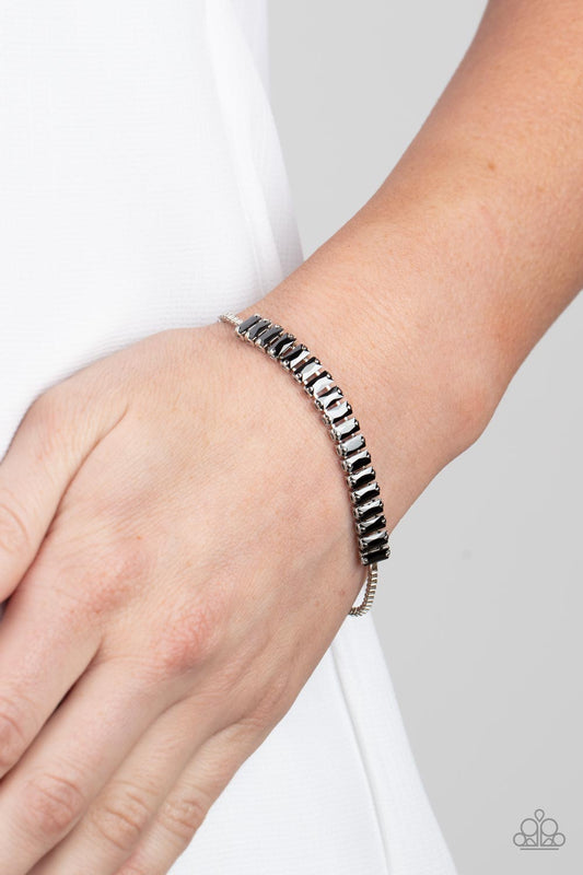 Glitz and Glimmer Silver Bracelet - Paparazzi Accessories  Encased in pronged silver fittings, a smoky collection of emerald cut hematite rhinestones delicately link with a silver box chain around the wrist, resulting in a versatile centerpiece. Features an adjustable sliding bead closure.  Sold as one individual bracelet.