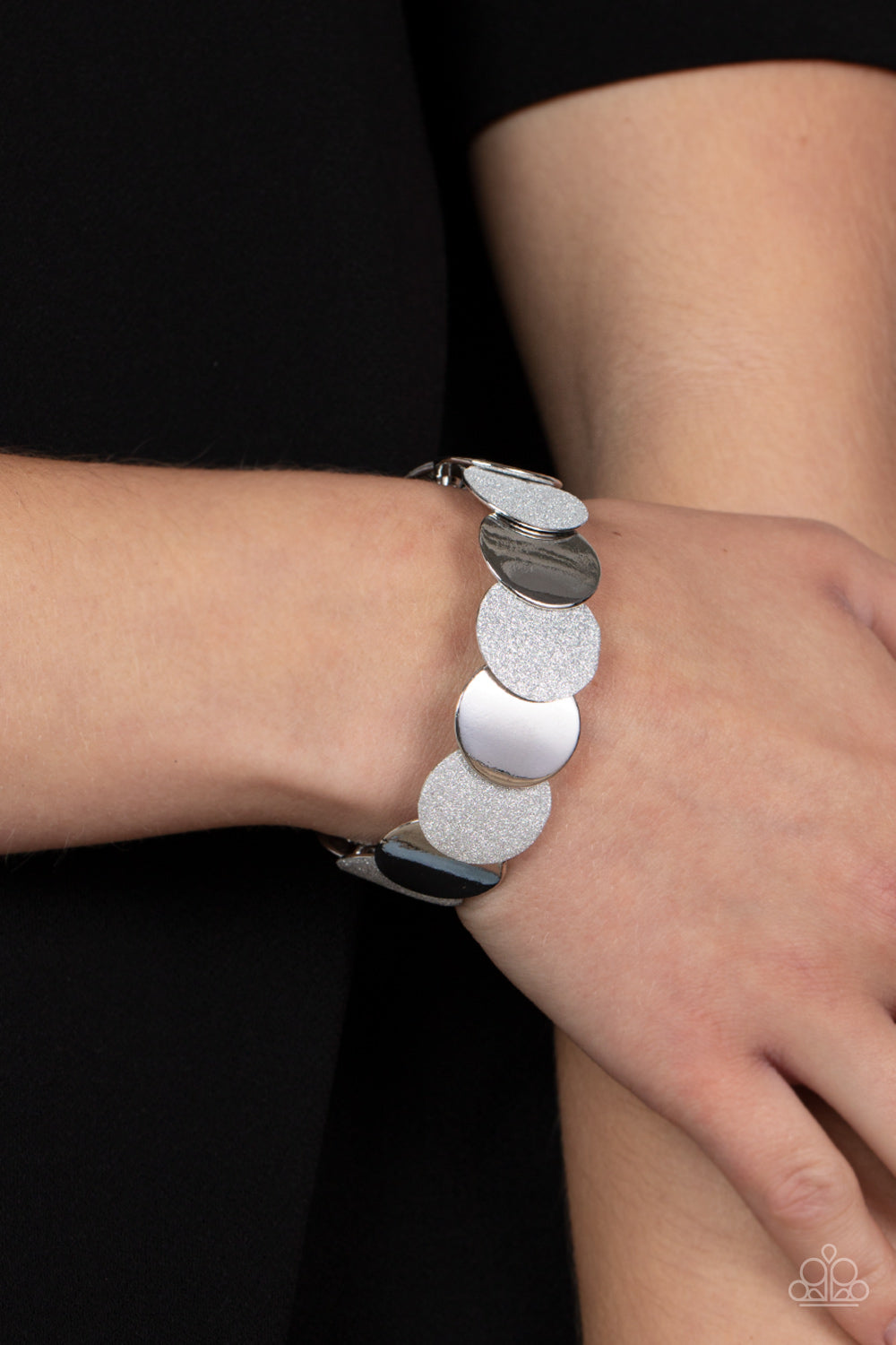 Demurely Disco Silver Bracelet - Paparazzi Accessories  A glimmering collection of shiny silver discs and glitter coated silver discs delicately overlap along stretchy bands around the wrist, creating a dazzling hint of shimmer.  Sold as one individual bracelet.