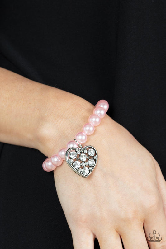 Cutely Crushing Pink Heart Bracelet - Paparazzi Accessories  A dramatically oversized white rhinestone encrusted silver heart charm dangles from a stretchy strand of bubbly pink pearls, creating a flirtatious dazzle.  Sold as one individual bracelet.