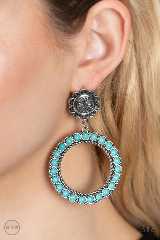 Playfully Prairie - Blue Item #P5CO-BLXX-056XX Featuring studded and twisted rope-like silver accents, a turquoise stone dotted hoop swings from the bottom of a rustic silver flower for a whimsically floral fashion. Earring attaches to a standard clip-on fitting.  Sold as one pair of clip-on earrings.