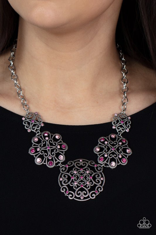 Royally Romantic Pink Necklace - Paparazzi Accessories  Spiraling with heart shaped filigree patterns, a mismatched collection of silver mandala-like frames delicately link below the collar. A smattering of dark and light pink rhinestones adorn the ornate frames, adding a spritz of glitter to the regal display. Features an adjustable clasp closure.  Sold as one individual necklace. Includes one pair of matching earrings.