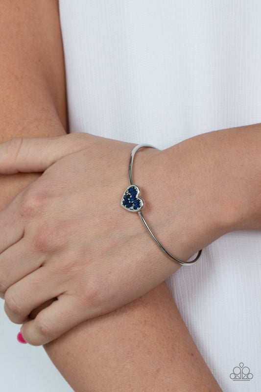 Heart of Ice Blue Cuff Bracelet - Paparazzi Accessories  A studded silver heart is encrusted in emerald cut blue rhinestones, creating a flirtatious centerpiece atop a dainty silver cuff.  Sold as one individual bracelet.