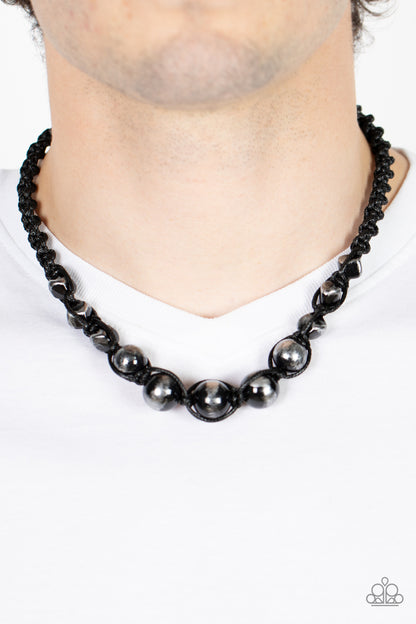 Loose Cannon Black Urban Necklace - Paparazzi Accessories  Brushed in shiny black accents, a gritty collection of faceted and round silver beads are knotted in place with braided black cording below the collar for an urban flair. Features a button loop closure.  Sold as one individual necklace.