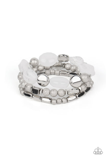 Marina Magic White Bracelet - Paparazzi Accessories  Infused with enchanting pops of white crystal-like and glassy accents, a mismatched assortment of hammered, cube, and faceted silver beads are threaded along stretchy bands around the wrist, creating shimmery layers.  Sold as one set of three bracelets.