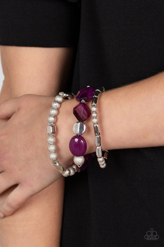 Marina Magic Purple Bracelet - Paparazzi Accessories  Infused with vivacious pops of plum crystal-like and glassy accents, a mismatched assortment of hammered, cube, and faceted silver beads are threaded along stretchy bands around the wrist, creating shimmery layers.  Sold as one set of three bracelets.