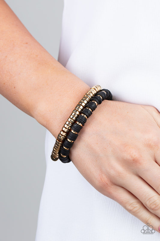 Catalina Marina Black Bracelet - Paparazzi Accessories  Infused with stretchy bands, a row of gold disc beads joins a strand of rubbery black and gold discs around the wrist, resulting in a modern duo.  Sold as one pair of bracelets.