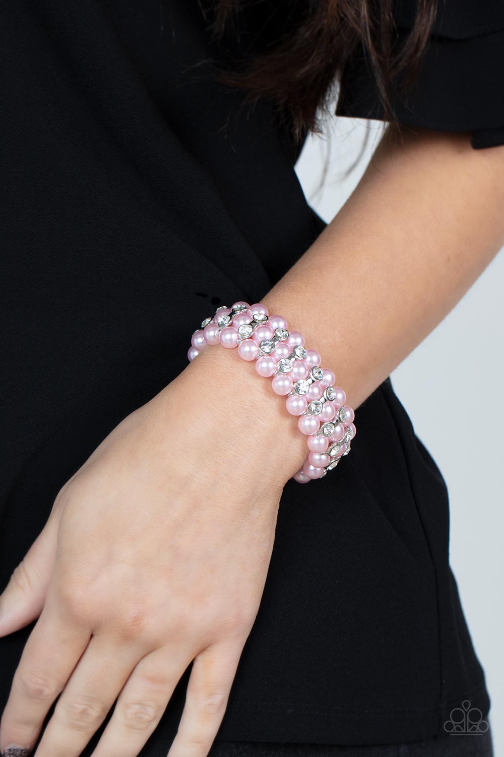 Eiffel Tower Elegance Pink Pearl Bracelet - Paparazzi Accessories  Stacked rows of bubbly pink pearls alternate with white rhinestone encrusted silver frames along stretchy bands, adding a timeless twist to the traditional pearl palette.  Sold as one individual bracelet.