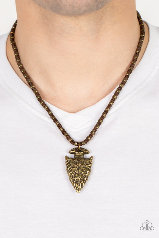 Get Your ARROWHEAD in the Game Brass Urban Necklace - Paparazzi Accessories  Dainty brass accents are knotted in place along a braided brown cord below the collar. Stamped and hammered in tribal inspired patterns, a rustic brass arrowhead pendant swings form the earthy display for an authentic finish. Features a button loop closure.  Sold as one individual necklace.