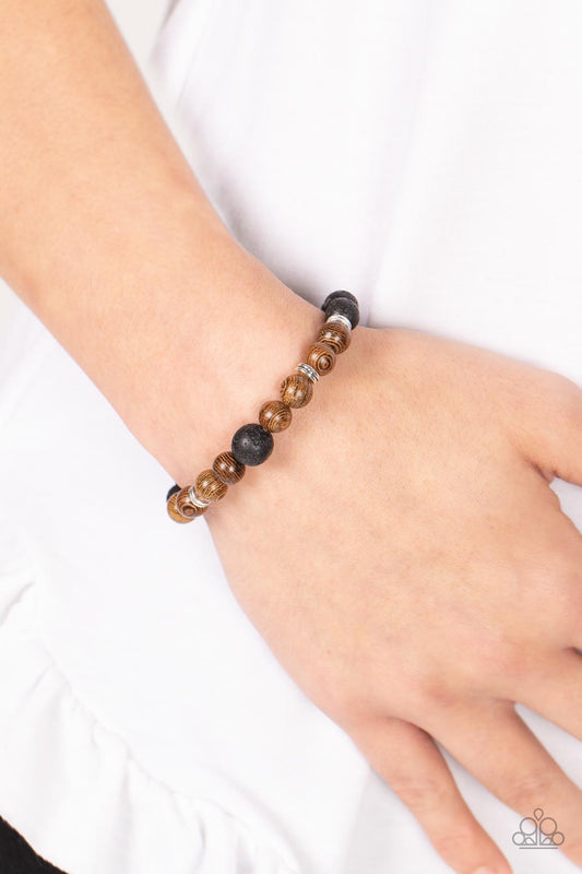 Neutral Zone Brown Bracelet - Paparazzi Accessories  Infused with dainty silver accents, an earthy compilation of brown wooden beads and black lava stone beads are threaded along stretchy bands around the wrist for an urban flair.  Sold as one individual bracelet.