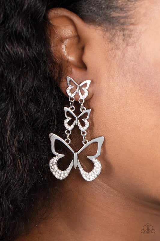 Flamboyant Flutter White Butterfly Earring - Paparazzi Accessories  An airy trio of silver butterflies gradually increase in size as they link into a whimsical lure. The bottom of each butterfly has been dipped in white rhinestones, adding a glitzy finish to the fluttering centerpiece. Earring attaches to a standard post fitting.  Sold as one pair of post earrings.