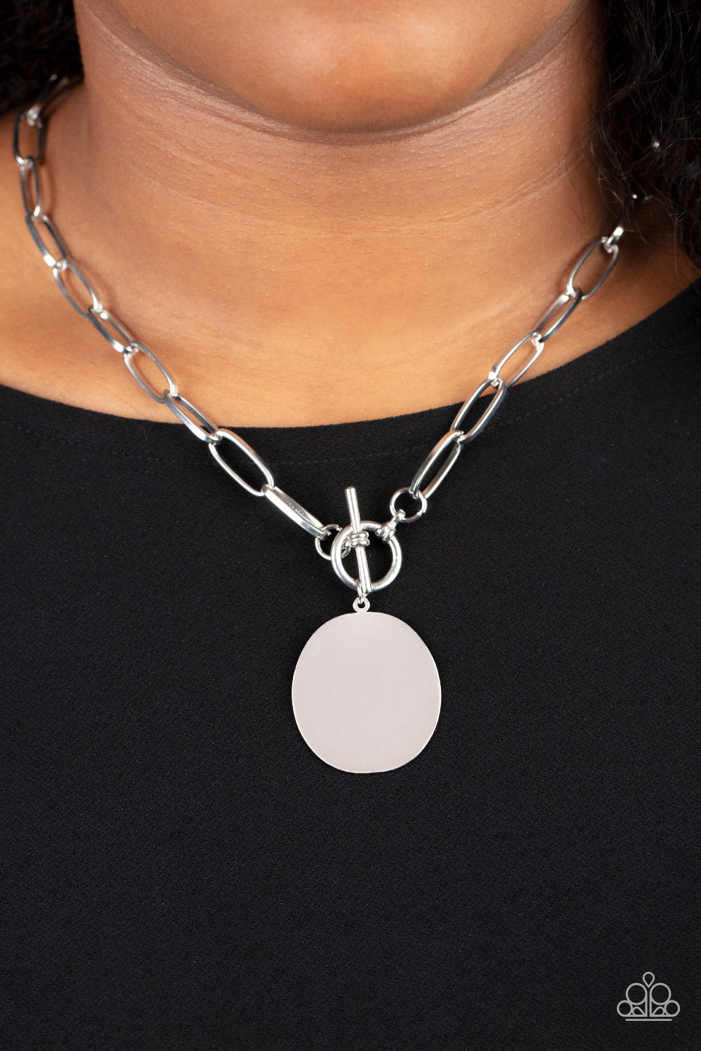 Tag Out Silver Necklace - Paparazzi Accessories  An oversized oval silver disc swings from the bottom of a substantial oval linked silver chain, resulting in a gritty industrial pendant below the collar. Features a toggle closure.  Sold as one individual necklace. Includes one pair of matching earrings.
