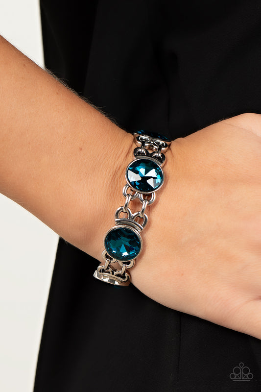 Devoted to Drama Blue Bracelet - Paparazzi Accessories  Featuring edgy chain-like fittings, a sparkly series of oversized blue rhinestones are threaded along stretchy bands around the wrist for a dramatic pop of glitz.  Sold as one individual bracelet.