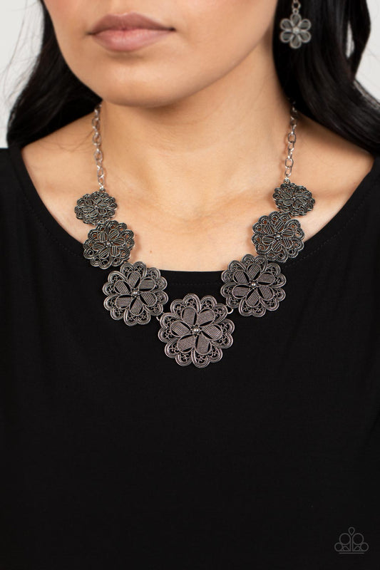 Basketful of Blossoms Silver Necklace - Paparazzi Accessories  Featuring metallic wicker-like patterns, stacks of teardrop and heart shaped filigree-filled silver petals delicately link into a decorative row of flowers. The floral frames gradually increase in size as they move towards the center, creating a vintage inspired display below the collar. Features an adjustable clasp closure.  Sold as one individual necklace. Includes one pair of matching earrings.