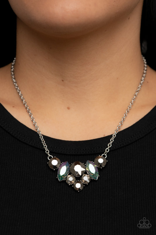 Lavishly Loaded Silver Necklace - Paparazzi Accessories  A smoldering collection of smoky, iridescent, and hematite gems of various cuts coalesces into a lavish frame at the bottom of a classic silver chain, resulting in a glamorous finish below the collar.  Sold as one individual necklace. Includes one pair of matching earrings.