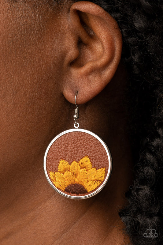 Sun-Kissed Sunflowers Brown Earring - Paparazzi Accessories  A golden yellow and brown threaded sunflower is stitched into the bottom of a brown leather frame that is encased in a sleek silver frame, resulting in a whimsical floral fashion. Earring attaches to a standard fishhook fitting.  Sold as one pair of earrings.