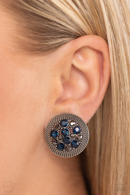 Stellar Status Blue Clip-On Earring - Paparazzi Accessories  A glitzy collection of blue and hematite rhinestones are encircled with a silver rope-like border, resulting in a smoldering centerpiece. Earring attaches to a standard clip-on earrings.  Sold as one pair of clip-on earrings.  New KitClip On Earring Sku:  P5CO-BLXX-055XX