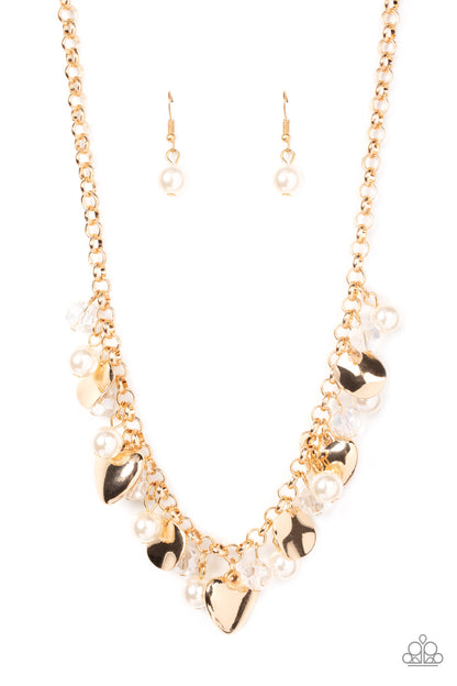 True Loves Trove Gold Necklace - Paparazzi Accessories  A flirtatious collection of white pearls, glassy white crystal-like beads, crinkled gold discs, and oversized locket inspired gold heart frames dance from a gold chain, resulting in a romantic fringe below the collar. Features an adjustable clasp closure.  Sold as one individual necklace. Includes one pair of matching earrings.