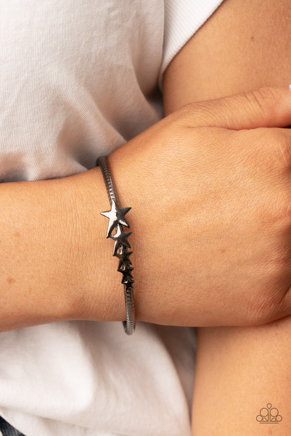 Astrological A-Lister Black Bangle Bracelet - Paparazzi Accessories  Glistening gunmetal stars graduate in size across the center of a textured gunmetal bangle, creating a stackable stellar centerpiece around the wrist.  Sold as one individual bracelet.