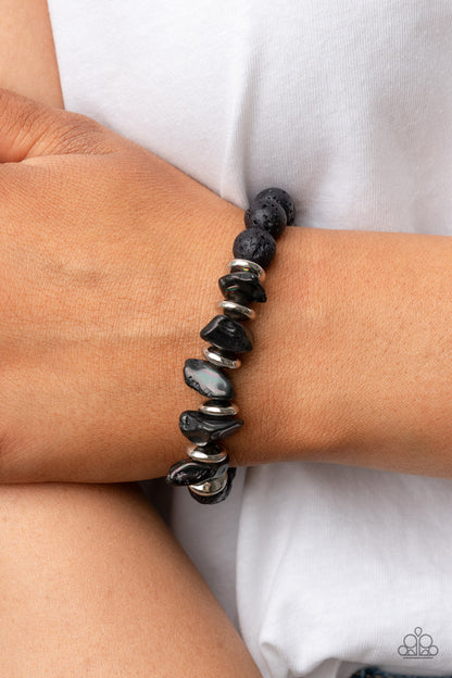 Volcanic Vacay Silver Bracelet - Paparazzi Accessories  An earthy collection of black lava rock beads, dainty silver discs, and black oil spill metallic pebbles are threaded along a stretchy band around the wrist, resulting in an edgy look. Due to its prismatic palette, color may vary.  Sold as one individual bracelet.