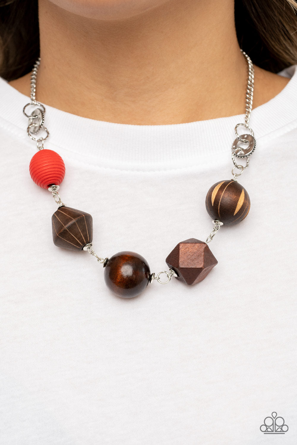 Eco Extravaganza Red Necklace - Paparazzi Accessories  Infused with a solitaire red wooden bead, a mismatched assortment of studded silver hoops, textured silver rings, and oversized brown wooden beads delicately connect across the chest for a stylishly handcrafted fashion. Features an adjustable clasp closure.  Sold as one individual necklace. Includes one pair of matching earrings.