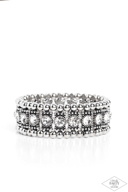 Ritzy Reboot White Bracelet - Paparazzi Accessories  A dazzling row of sparkling white rhinestones set in dotted frames is bordered by a row of dainty antiqued silver studs. Shiny round silver beads form the outermost border of this luxuriously layered design, which is threaded along stretchy bands for an upscale edgy look. P9ED-WTXX-034EE This Black Diamond Encore is back in the spotlight at the request of our 2022 Life of the Party member with Black Diamond Access, Tracey G.