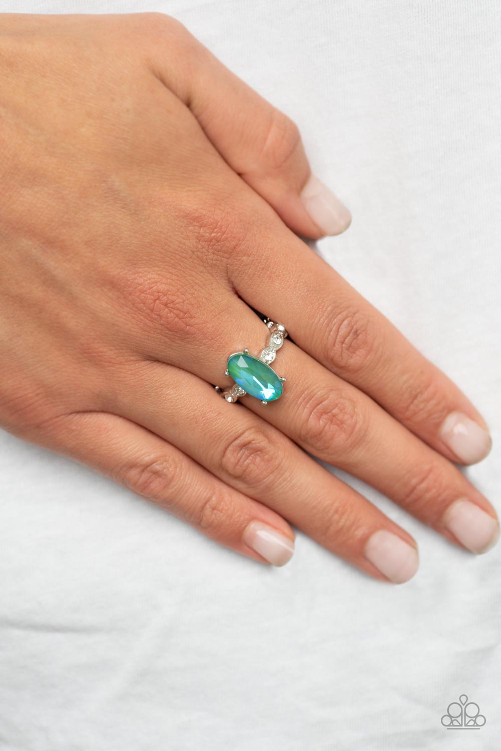 Stellar Sensation Green Ring - Paparazzi Accessories  Featuring a blue UV finish, an iridescent green oval rhinestone is nestled inside a pronged silver frame atop a dainty band of white rhinestones for a stellar fashion. Features a dainty stretchy band for a flexible fit.  Sold as one individual ring.