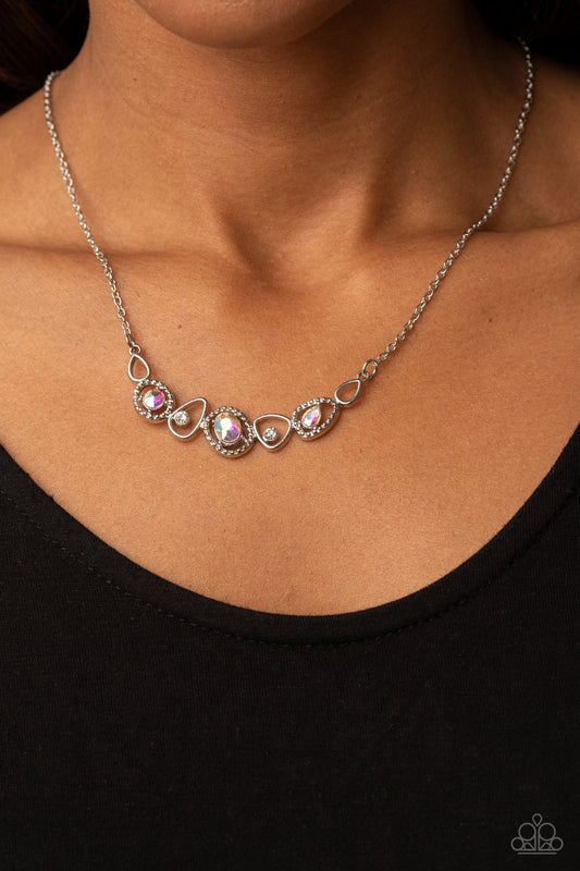 Celestial Cadence Multi Necklace - Paparazzi Accessories  An incandescent assortment of shiny silver frames, dainty white rhinestones, and oversized iridescent gems delicately coalesce into a statement-making sparkle below the collar. Features an adjustable clasp closure.  Sold as one individual necklace. Includes one pair of matching earrings.