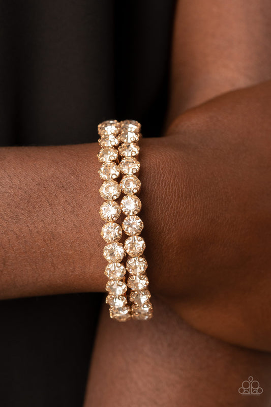 Megawatt Majesty Gold Cuff Bracelet - Paparazzi Accessories  Encased in sleek gold fittings, two oversized rows of glassy white rhinestones stack into a blinding cuff around the wrist for a jaw-dropping look.  Sold as one individual bracelet.