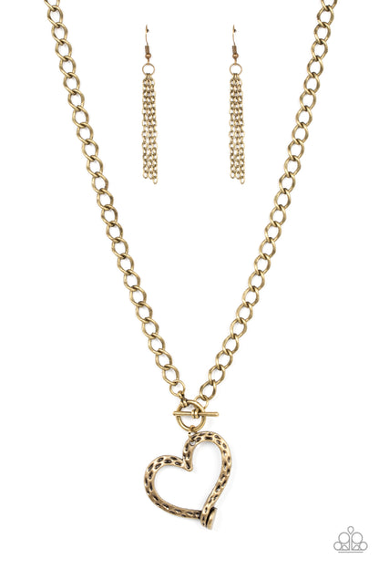 Reimagined Romance Brass Necklace - Paparazzi Accessories  A hammered brass heart frame gently twists from a toggle closure at the bottom of a chunky brass chain, resulting in a romantically rustic pendant. Features a toggle closure.  Sold as one individual necklace. Includes one pair of matching earrings.
