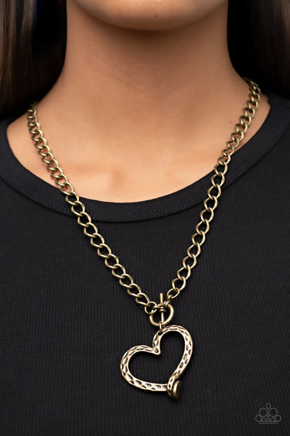 Reimagined Romance Brass Necklace - Paparazzi Accessories  A hammered brass heart frame gently twists from a toggle closure at the bottom of a chunky brass chain, resulting in a romantically rustic pendant. Features a toggle closure.  Sold as one individual necklace. Includes one pair of matching earrings.