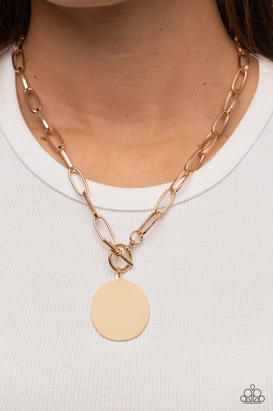 Tag Out Gold Necklace - Paparazzi Accessories  An oversized oval gold disc swings from the bottom of a substantial oval linked gold chain, resulting in a gritty industrial pendant below the collar. Features a toggle closure.  Sold as one individual necklace. Includes one pair of matching earrings.