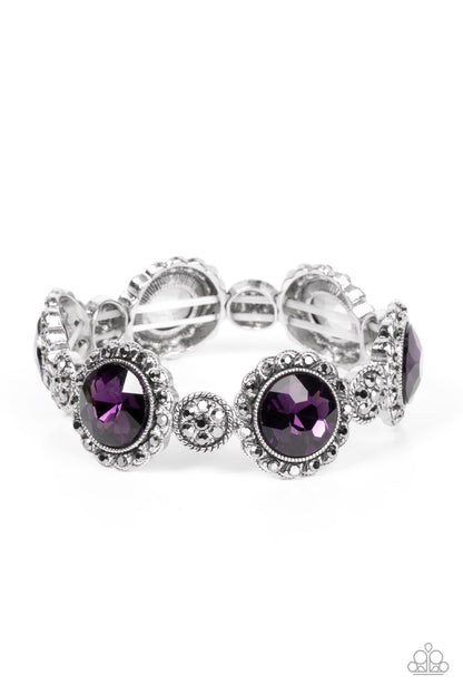 Palace Property Purple Bracelet - Paparazzi Accessories  An oversized purple rhinestone adorns the center of a hematite rhinestone petaled floral frame. Infused with hematite dotted silver accents, the glitzy floral frames sparkle along stretchy bands around the wrist for a glamorous finish.  Sold as one individual bracelet.